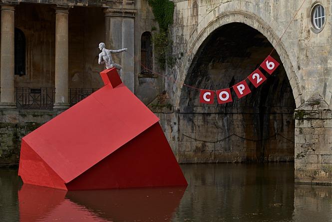 Red house sinking in river with COP26 sign